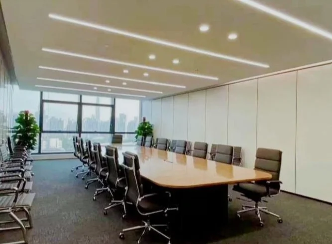 Large boardroom with a long polished conference table, floor-to-ceiling glazing and linear ceiling lighting