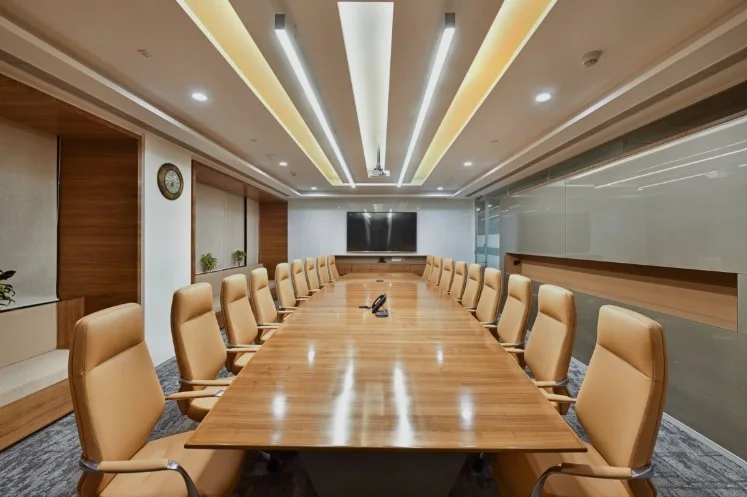 Executive boardroom with a polished wood table, tan leather chairs and an illuminated cove ceiling