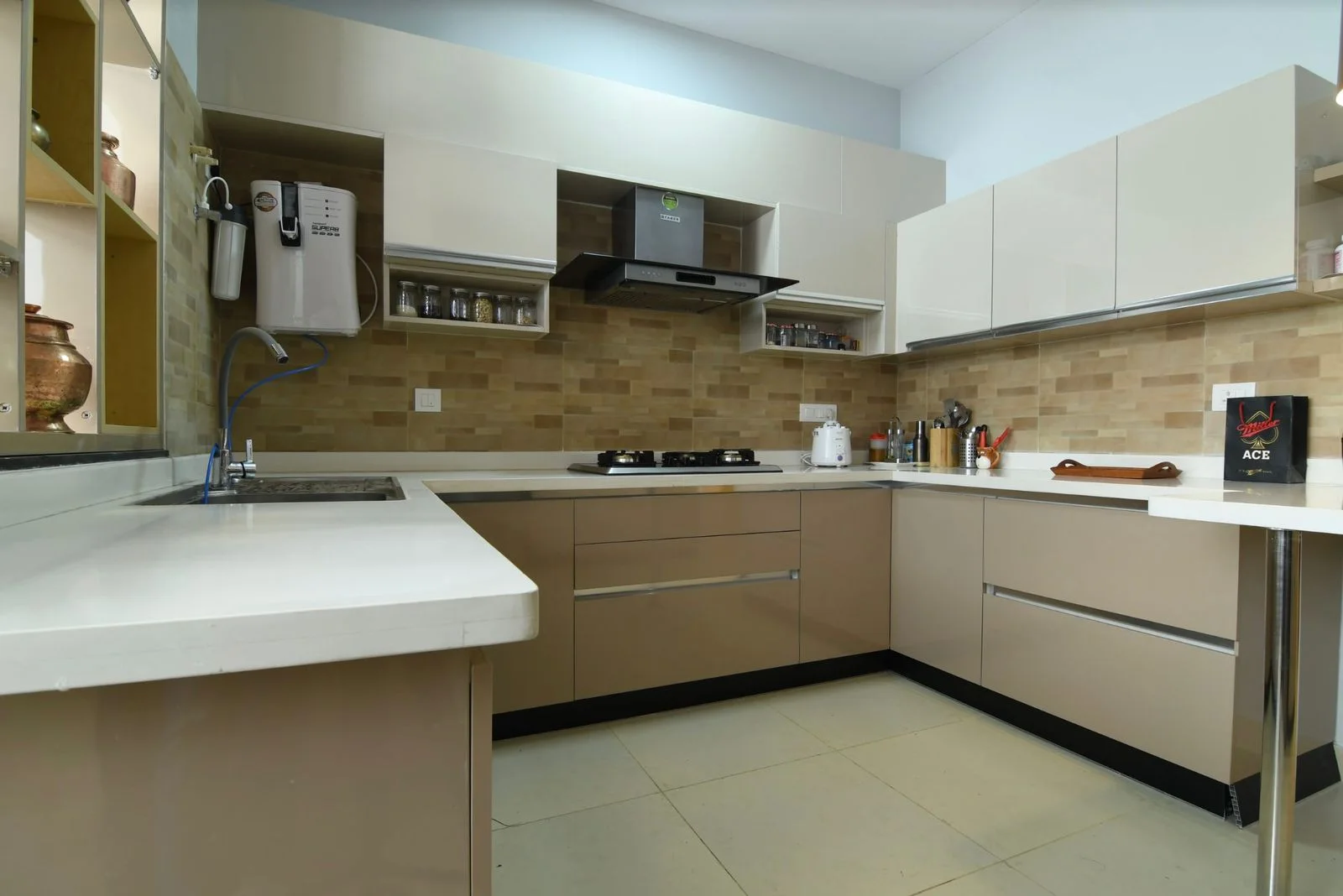 L-shaped modular kitchen with beige gloss laminate shutters and a white quartz countertop