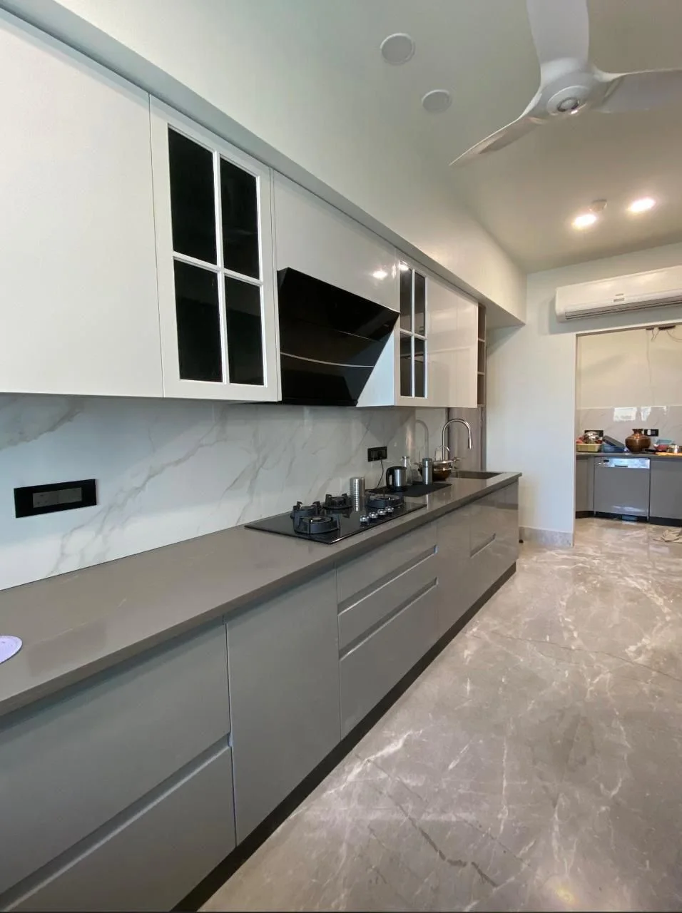 Parallel modular kitchen with grey gloss base units and glass-fronted wall cabinets